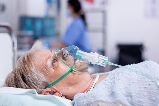 Old woman breathing with oxygen mask laying in hospital bed getting treatment for infection with coronavirus. Medicine medical healthcare system epidemic lungs infection treatment