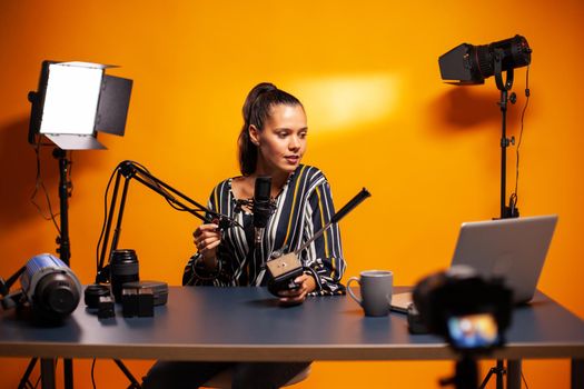 Woman videographer holding fluid head plate while recording testimonial. Social media star making online internet content about video equipment for web subscribers and distribution, film