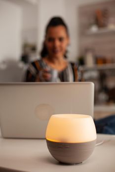 Woman using laptop enjoying aromatherapy from oil diffuser Aroma health essence, welness home spa fragrance tranquil theraphy, therapeutic steam, mental health treatment