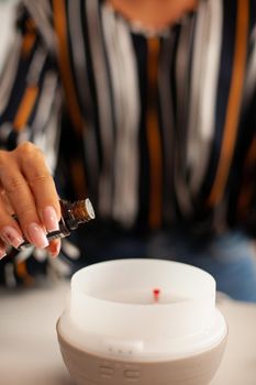 Pouring essential oils into diffuser for aromatherapy. Aroma health essence, welness home spa fragrance tranquil theraphy, therapeutic steam, mental health treatment
