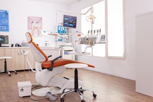 Empty stomatology orthodontist hospital office room equipped with teethcare instruments and dental medical chiarequipment. Orthodontic cabinet prepared for dentistry healthcare treatment