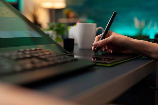 Close up of artistic hand using digital tablet and stylus while retouching image design at professional studio office desk. Woman doing editing work on editor software with modern equipment