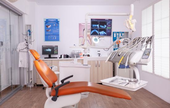 Empty professional dentistry stomatology hospital office room with nobody in it. Modern orthodontic clinic equipped with medical teethcare furniture and tooth instruments ready for oral surgery