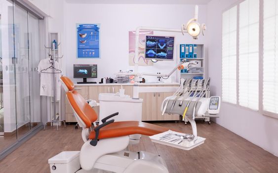 Empty stomatology orthodontist hospital office room with nobody in it prepared for teeth healthcare treatment. Medical dentistry cabinet with tooth xray images on monitor, surgery tools instrument