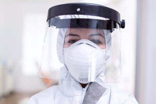 Close up portrait of exhausted doctor with face shield and face mask against fight with coronavirus. Medical personal dressed in protection equipment against infection with covid-19 during global pandemic.
