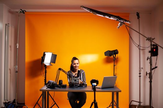 Videographer showing battery with v-mount in home studio for podcast. Professional videography gear review by content creator new media star influencer on social media.