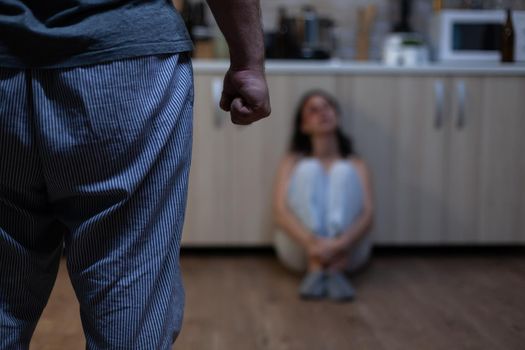 Close up of clenched fist of aggressive man after abusing woman, during domestic violence and physical trauma. Violent husband threatening helpless hurt wife with bruises on face