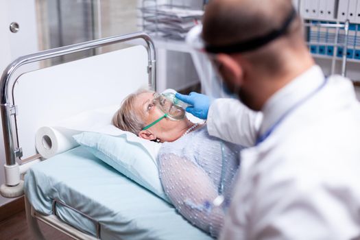 Patient breathing heavily without oxygen mask in emergency hospital room. Doctor helping old woman with pulmonary disease. Medicine medical healthcare system epidemic lungs infection treatment