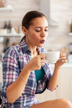 Close up of woman holding a cup of hot green tea trying to drink it.