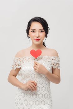 Elegant Asian woman holding a parper heart and standing isolated over white background.