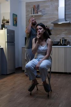 Unhappy terrified woman sitting and smoking cigarette feeling miserable after domestic violence and physical abuse from violent man. Aggressive drunk husband harassing bruised wife