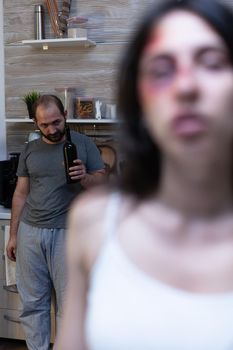 Woman having domestic violence bruises from partner while alcoholic angry man threatening to beat and fight. Couple with aggression issues feeling depressed in relationship, marriage