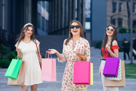 Young Girls with colorful shopping bags walking around the city after shopping. Consumerism, purchases, shopping, lifestyle concept. Women in shopping.