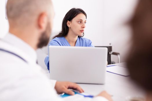 Nurse listening medical specialist during briefing about patient diagnosis in hospital conference room. Clinic therapist with colleagues talking about disease, expert,specialist, communication.