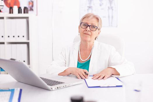 Portrait of medical doctor woman smiling looking at camera in hospital office wearing lab coat. Medical practitioner using notebook in clinic workplace , confident, expertise, medicine.