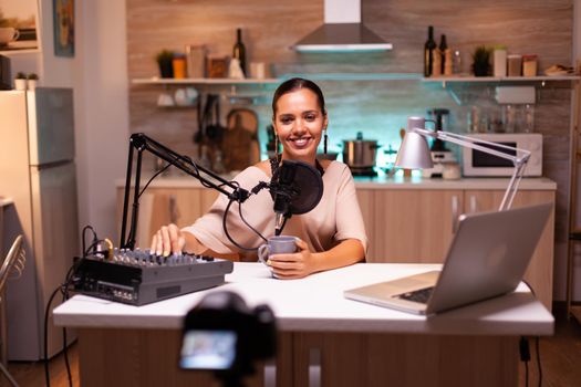 Person speaking about her life during podcast in home studio with neon light behind her. Creative online show On-air production internet broadcast host streaming live content.