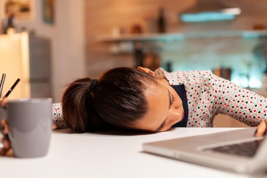 Woman falling asleep with head on the table while working from home on a deadline. Employee using modern technology at midnight doing overtime for job, business, career, network, lifestyle ,wireless.