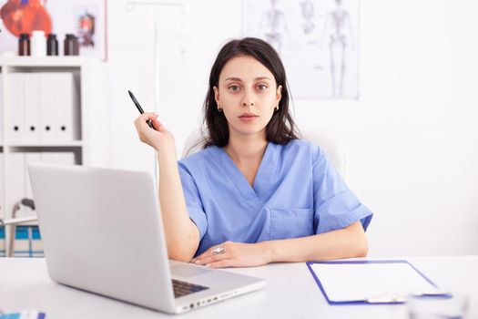 Portrait of a female doctor using her laptop computer at clinic. Medical practitioner using notebook in hospital workplace , confident, expertise, medicine.