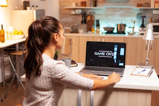 Game over for woman playing video games on laptop during night time Professional gamer playing online videop games on her personal computer. Geek cyber e-sport.