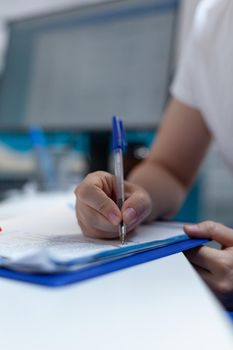 Closeup of woman patient signing medical documents during clinical consultation in hospital office. African american therapist doctor explaining disease symptoms discussing medication treatment