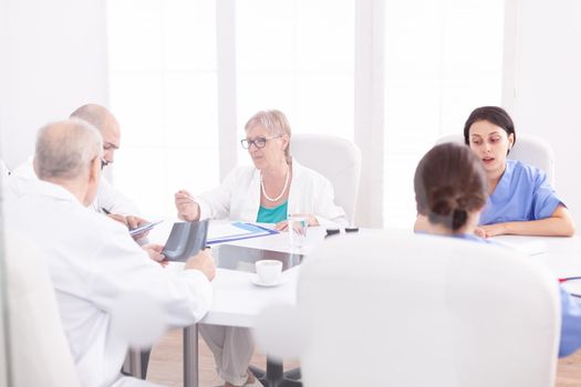 Team of expert doctors sitting at desk in conference room having a briefing. Clinic expert therapist talking with colleagues about disease, medicine professional