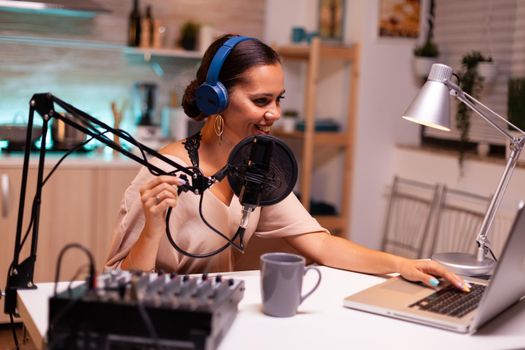 Vlogger speaking with follower on live using professional microphone wearing headphones. Creative online show On-air production internet broadcast host streaming live content and recording