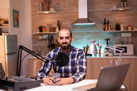 Influencer holding coffee cup and recording podcast in home studio. Creative online show On-air production internet broadcast host streaming live content, recording digital social media communication