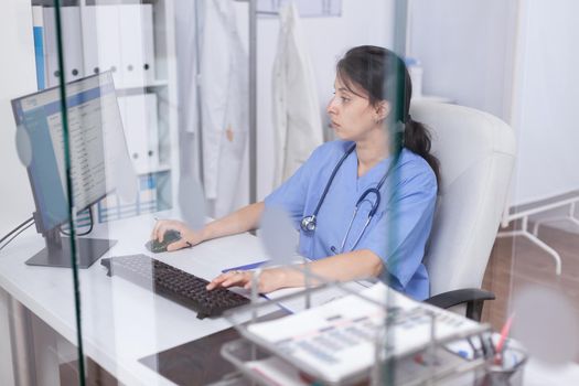 Nurse in hospital office working on computer. Healthcare physician specialist in medicine providing health care services treatment examination.