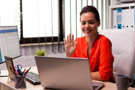 Businesswoman talking with team using internet connection during online meeting. Entrepreneur using internet connection for video meeting with coworkers looking at webcam.