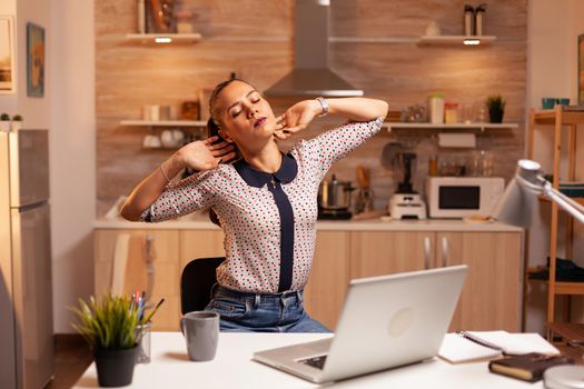 Freelance woman stretching arms because of exhaustion while working overtime from home. Employee using modern technology at midnight doing overtime for job, business, busy, career, network, lifestyle ,wireless.