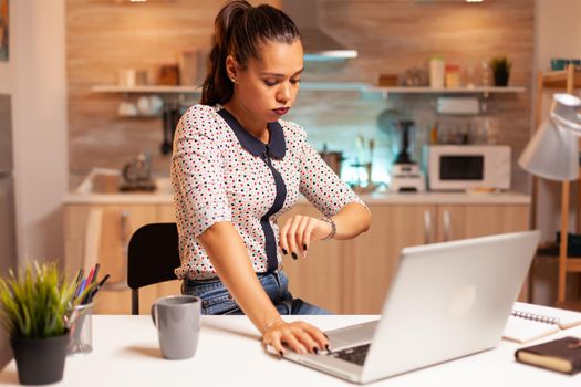 Exhausted businesswoman checking time on watch before project deadline. Employee using modern technology at midnight doing overtime for job, business, busy, career, network, lifestyle ,wireless.