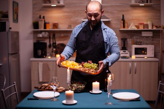Guy waiting wife for romantic dinner in kitchen with festife food. Man preparing festive dinner with healthy food, cooking for his woman a romantic dinner,