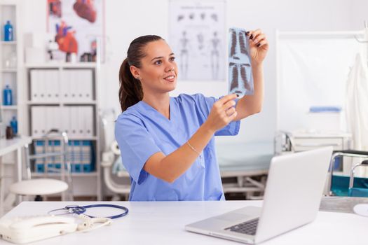 Medical nurse holding patient radiography in hospital office. Radiologist in medical uniform holding and looking at x-ray, examination, bone, practitioner, analyze, diagnosis.
