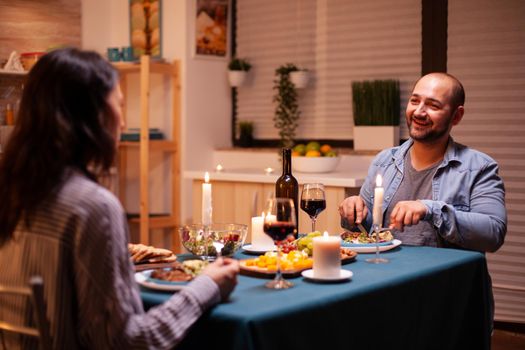 Lovers enjoying tasty food while having dinner in kitchen. Relax happy people, sitting at table in kitchen, enjoying the meal, celebrating anniversary in the dining room.