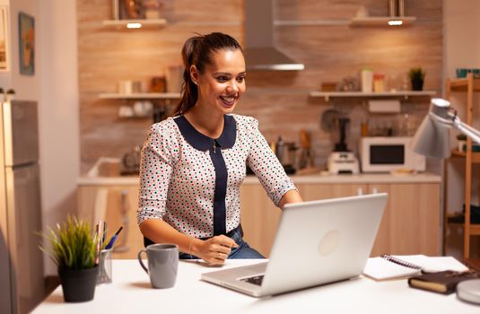 Businesswoman reacting with excitement while working on important project in the evening. Employee using modern technology at midnight doing overtime for job, business, career, network, lifestyle.