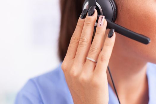 Medical secretary having a conversation with patients while wearing headphones with microphone. Female nurse, doctor during call examination with sick person during consultation, medicine.