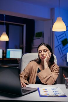 Overworked manager working on financial deadline sitting at desk. Smart woman sitting at her workplace in the course of late night hours doing her job.