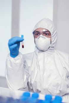 Biochemist in ppe suit looking and working with blood in test tube. Doctor working with various bacteria and tissue, pharmaceutical research for antibiotics against covid19.