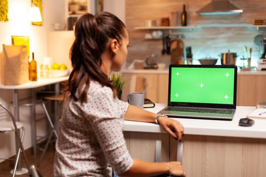 Woman using laptop with green mockup. Sitting at desk works on computer late at night, business, online, smart, blank, copyspace, digital, display.