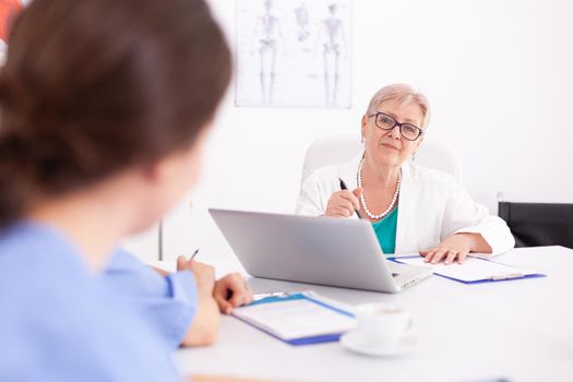 Nurse listening mature doctor during medical conference in hospital. Clinic therapist with colleagues talking about disease, expert,specialist, communication.