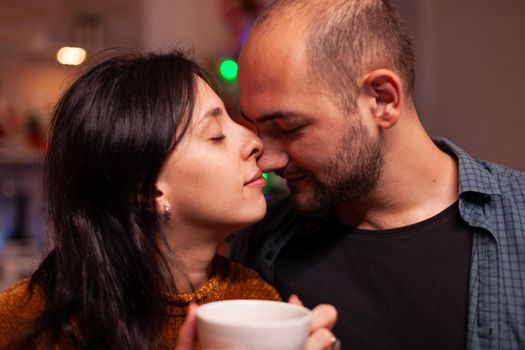 Portrait of happy couple enjoying christmas holiday spending time together in xmas decorated kitchen. Family celebrating santa-claus season during winter season. New-year festive tradition