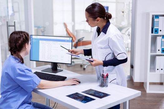 Dentistiry practitioer and nurse looking at patients appointments for the day in teeth clinic. Stomatology assistant and teeth doctor discussing in reception of dental office