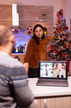 Angry nervous upset girlfriend waiting busy boyfriend to spend time with her during christmas festive holiday enjoying winter season together. Man having business online business videocall