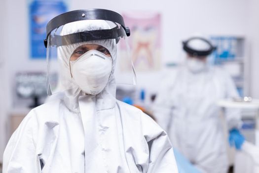 Dentist looking exhausted at camera dressed in coverall in the course of covid-19 pandemic. Portrait of tired stomatologist wearing coronavirus ppe suit looking at camera.