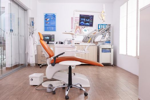 Empty professional stomatology hospital office room with nobody in it equipped with modern orthodontic furniture. Teeth radiography images on monitor revealing tooth dental medical diagnosis