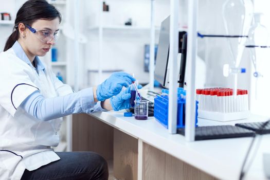 Woman scientist in healthcare industry taking sample from test tube using glass pipette. Chemistry scientist in sterile laboratory using modern technology to test microbiology liquid.