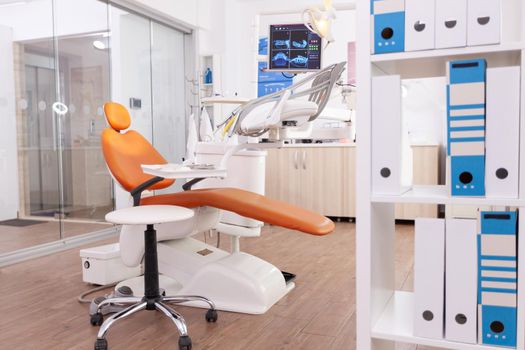 Interior of stomatology orthodontic hospital office with nobody in it ready for dental surgery equipped with modern dentistry tooth instruments. Medical room with teeth xray images on display