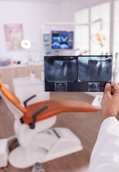 Orthodontist radiologist holding medical tooth radiography in hands analyzing dentistry surgery expertise. Specialist doctor working in stomatology dental orthodontic hospital office room