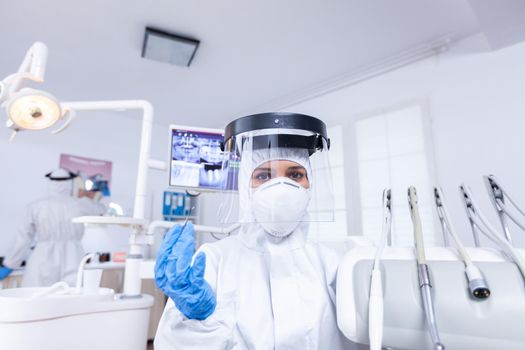 Pov of patient sitting on chair at dental office for teeth treatment Stomatolog wearing safety gear against coronavirus during heatlhcare check of patient.