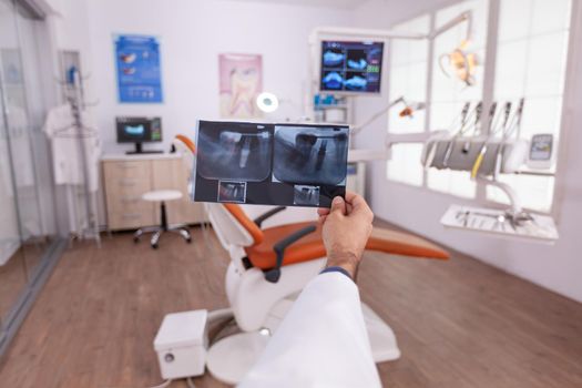 Radiologist doctor holding oral dental teeth radiography examining teethcare expertise working in stomatology hospital office. Orthodontist man analyzing surgery diagnosis in examination room